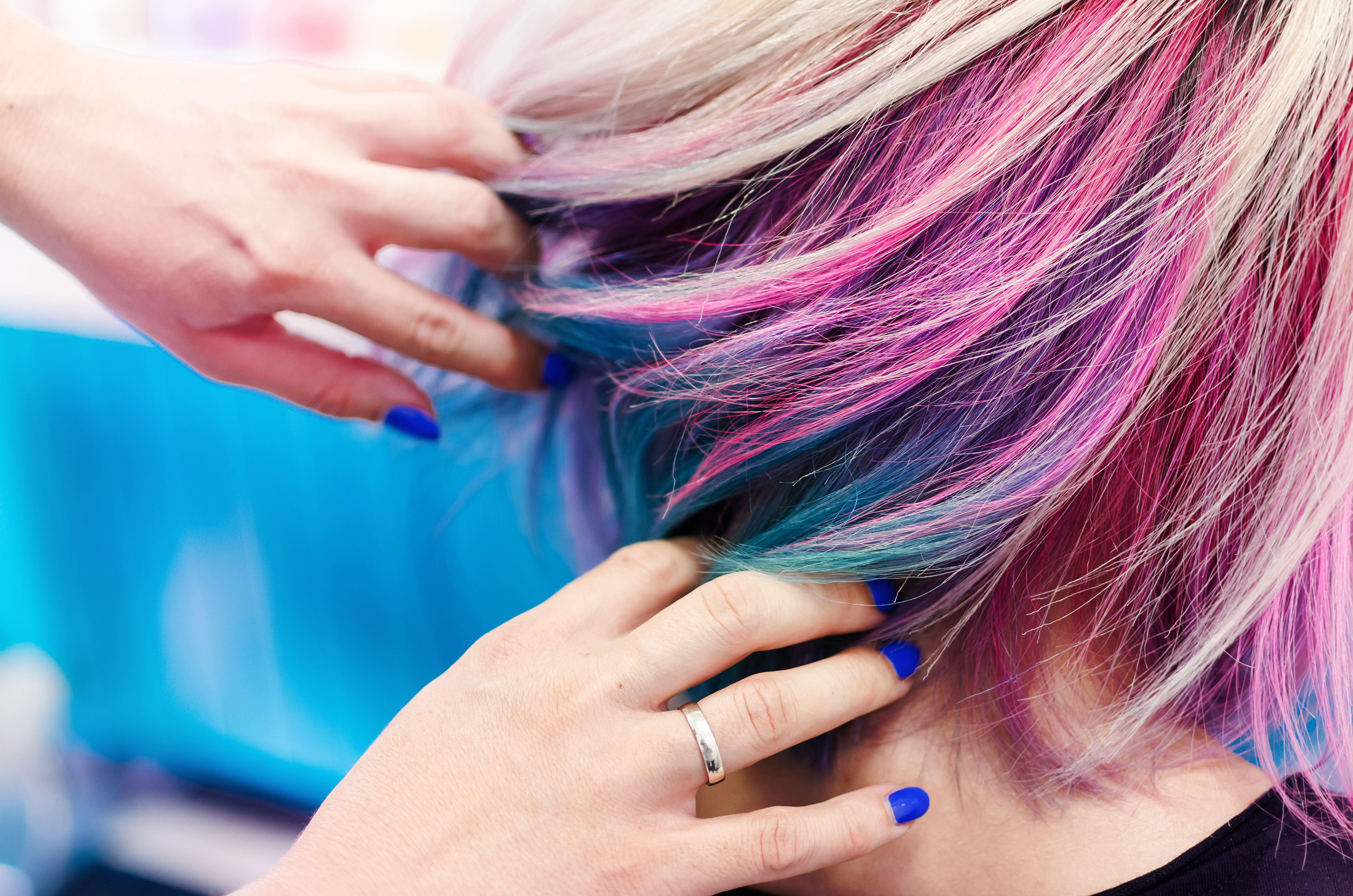 Hairdressers hands in colorful client head and hair after coloring or hair dyeing.