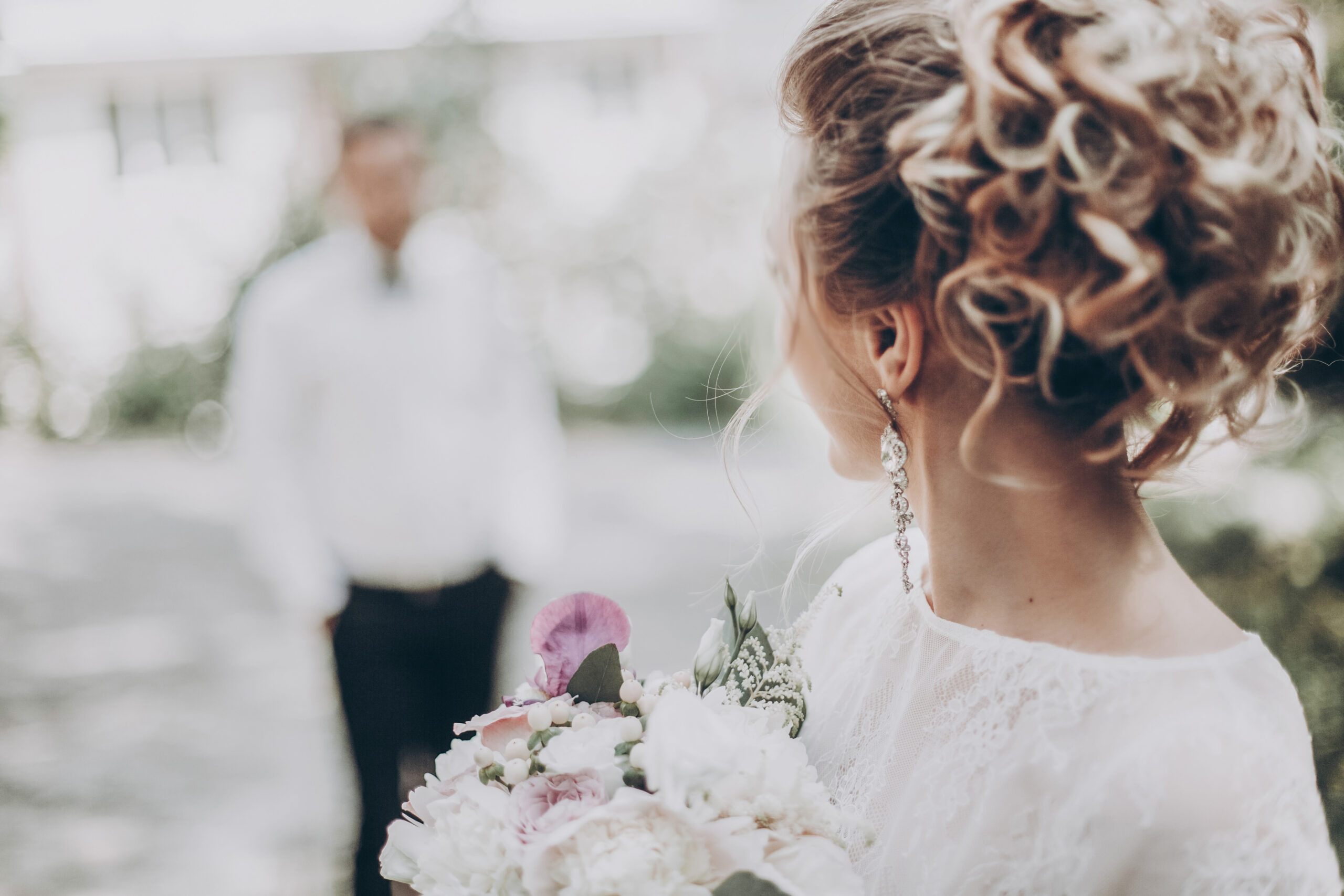 stylish wedding bride with bouquet and amazing modern dress. bride posing and looking at groom in sunny garden, fine art wedding photo, romantic moment, long edge